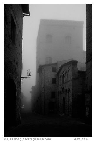 Street and medieval tower at dawn in the fog. San Gimignano, Tuscany, Italy