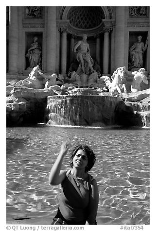 Tourist tosses a coin over her shoulder in the Trevi Fountain. Rome, Lazio, Italy