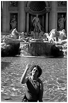 Tourist tosses a coin over her shoulder in the Trevi Fountain. Rome, Lazio, Italy (black and white)