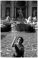 Tourist tosses a coin over her shoulder in the Trevi Fountain. Rome, Lazio, Italy ( black and white)