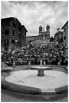 Fontana della Barcaccia and Spanish Steps covered with tourists sitting. Rome, Lazio, Italy (black and white)