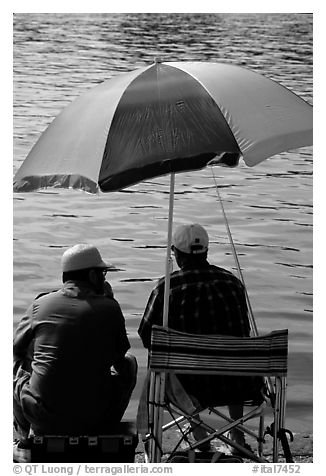Men fishing under an colorful sun unbrella,  Agropoli. Campania, Italy (black and white)