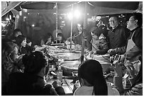 People eating noodles in a tent at night. Seoul, South Korea ( black and white)