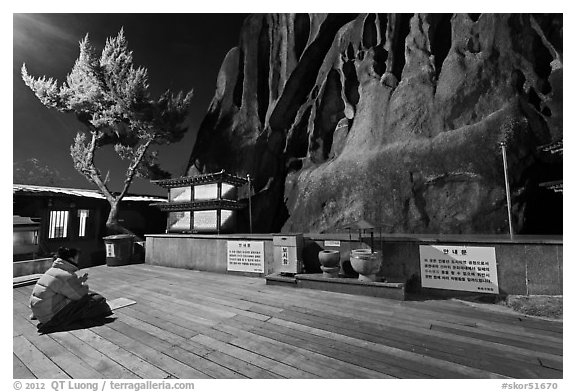 Woman wearing parka worshipping at Seon-bawi. Seoul, South Korea (black and white)