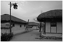 Alley bordered by straw roofed houses. Hahoe Folk Village, South Korea (black and white)