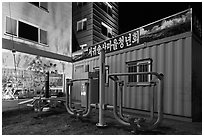 Public exercise equipment and buildings at night, Seogwipo. Jeju Island, South Korea (black and white)