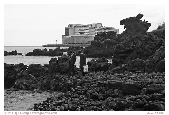 Businessmen on shore near Yongduam Rock, Jeju-si. Jeju Island, South Korea (black and white)