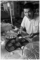 Man preparing mini-pancakes. George Town, Penang, Malaysia (black and white)