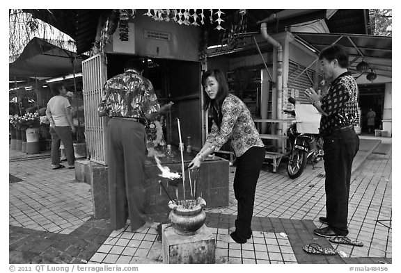 Worshiping at Buddhist street altar. George Town, Penang, Malaysia (black and white)