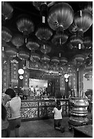 Woman in prayer, altar and lanters, Kuan Yin Teng temple. George Town, Penang, Malaysia (black and white)