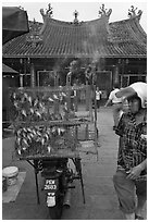 Motorcycle loaded with cage of birds (to be freed) in front of temple. George Town, Penang, Malaysia (black and white)