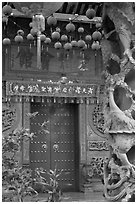 Red paper lanters, door, and stone carved wall, Hainan Temple. George Town, Penang, Malaysia (black and white)