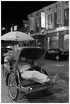 Driver taking nap in trishaw at night. George Town, Penang, Malaysia (black and white)