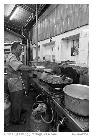 Man frying food in large pan. George Town, Penang, Malaysia