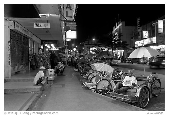 Cycle rickshaws lined on street at night. George Town, Penang, Malaysia (black and white)