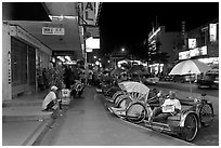 Cycle rickshaws lined on street at night. George Town, Penang, Malaysia ( black and white)