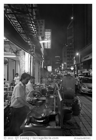 Cooks preparing food on Chinatown street at night. Kuala Lumpur, Malaysia