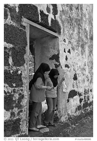 Malay girls exit on St Paul church doorway. Malacca City, Malaysia (black and white)