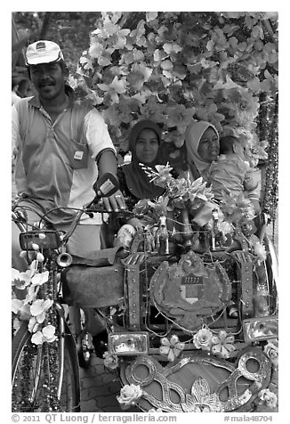 Decorated trishaw driver and passengers. Malacca City, Malaysia (black and white)