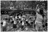 Schoolchildren doing gymnastics in  Singapore Botanical Gardens. Singapore (black and white)