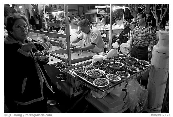 Woman eating by a street food stand , Tlaquepaque. Jalisco, Mexico