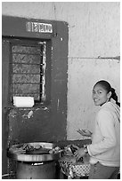 Woman preparing food outside a blue wall, Tonala. Jalisco, Mexico (black and white)
