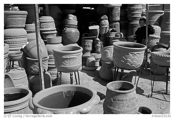 Boy standing next to clay pots, Tonala. Jalisco, Mexico (black and white)