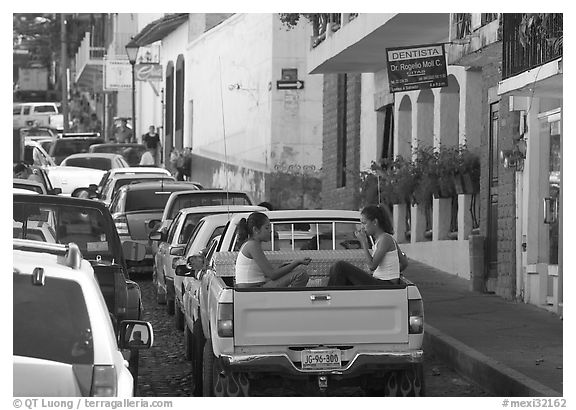 Young women riding in the back of a pick-up truck in a busy street, Puerto Vallarta, Jalisco. Jalisco, Mexico (black and white)
