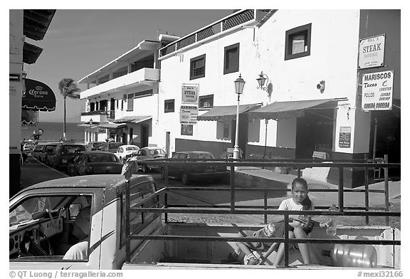 Girl riding in the back of pick-up truck in a street close to ocean, Puerto Vallarta, Jalisco. Jalisco, Mexico