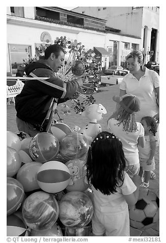 Children, mother, and balloon vendor , Puerto Vallarta, Jalisco. Jalisco, Mexico (black and white)