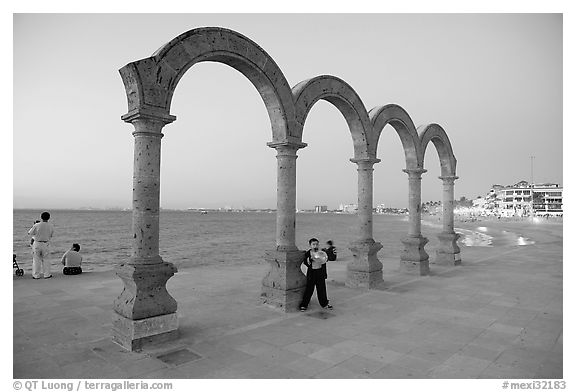 Boy standing by the Malecon arches at dusk, Puerto Vallarta, Jalisco. Jalisco, Mexico (black and white)