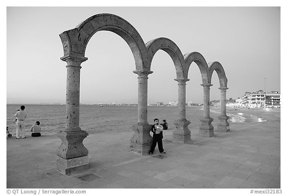 Boy standing by the Malecon arches at dusk, Puerto Vallarta, Jalisco. Jalisco, Mexico