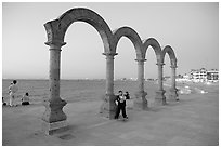 Boy standing by the Malecon arches at dusk, Puerto Vallarta, Jalisco. Jalisco, Mexico (black and white)