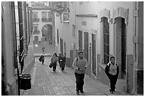 Children heading to school up a narrow cajaon, dawn. Zacatecas, Mexico (black and white)