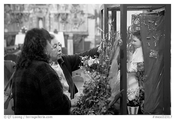 Women placing flowers in front of a Saint figure. Zacatecas, Mexico (black and white)