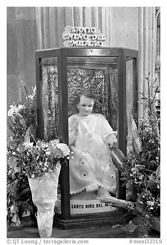 Figure of Santo Nino Del Milagro with offered flowers. Zacatecas, Mexico (black and white)