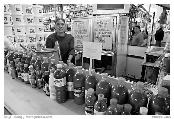Woman at a booth with lots of chili bottles in Mercado Hidalgo. Guanajuato, Mexico (black and white)