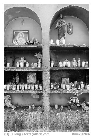 Candles, flowers, and religious offerings in a roadside chapel. Mexico (black and white)