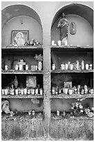 Candles, flowers, and religious offerings in a roadside chapel. Mexico (black and white)