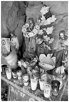 Religious figures and candles in roadside chapel. Mexico (black and white)