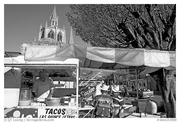 Taco stand on town plaza with cathedral in background. Mexico (black and white)