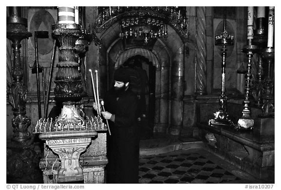 Christian Orthodox priest lighting candles. Jerusalem, Israel (black and white)