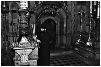Christian Orthodox priest lighting candles. Jerusalem, Israel ( black and white)