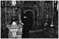 Christian Orthodox priest lighting candles. Jerusalem, Israel (black and white)