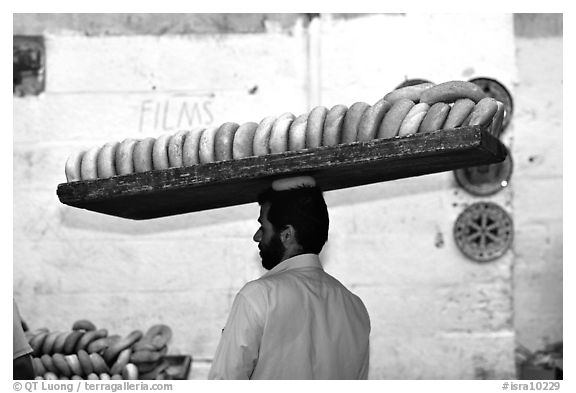 Man carrying many loafes of bread on his head. Jerusalem, Israel (black and white)