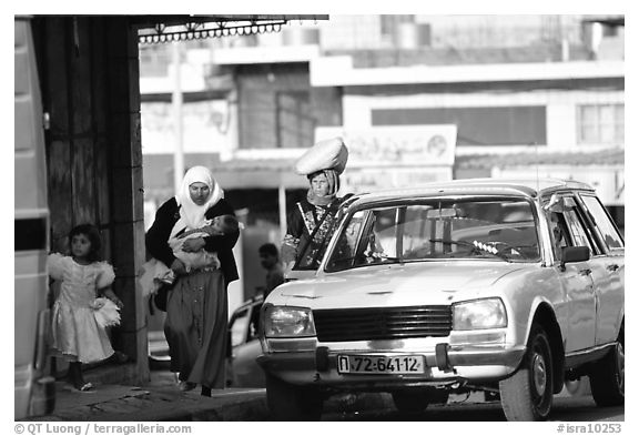 Women next to an old French Peugeot car, Hebron. West Bank, Occupied Territories (Israel)