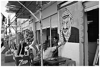 Palestinian cafe owner pointing proudly to a painting of Yasser Arafat, Jericho. West Bank, Occupied Territories (Israel) (black and white)