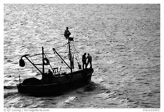 Small fishing boat silhouetted, late afternoon, Akko (Acre). Israel (black and white)