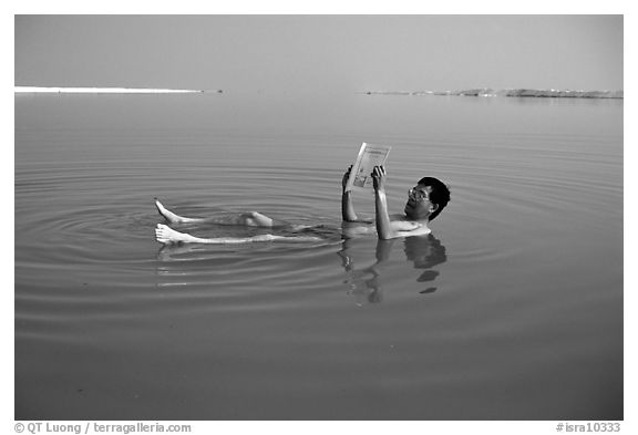 Visitor reading while floating in the Dead Sea. Israel (black and white)