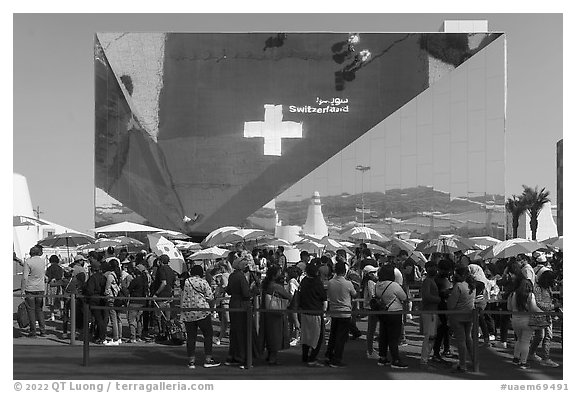 Visitors with umbrellas and reflection, Swizerland Pavilion. Expo 2020, Dubai, United Arab Emirates